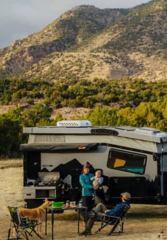 Une famille se détend à côté de son camping-car dans les montagnes